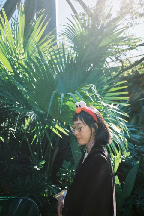 woman in black top standing beside palm plants