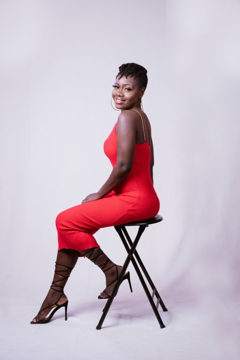 a woman in a red dress sitting on a stool