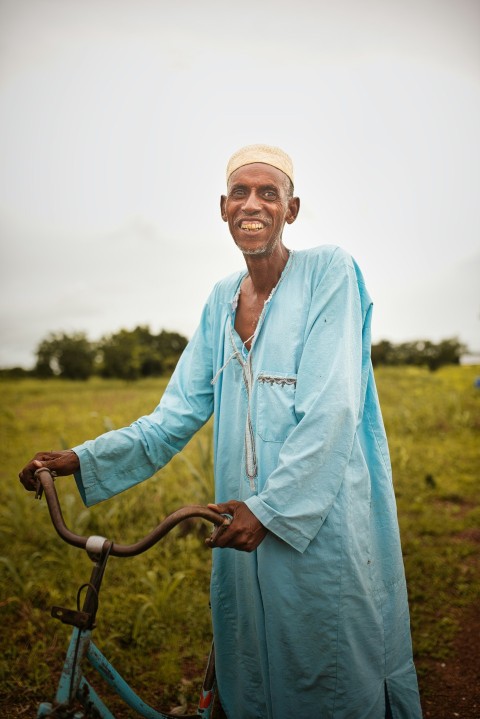 a man in a blue robe holding a bicycle