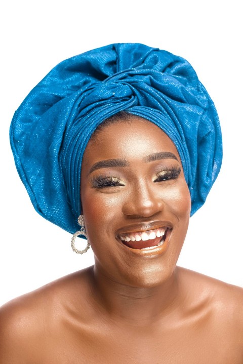 a woman wearing a blue turban smiles at the camera