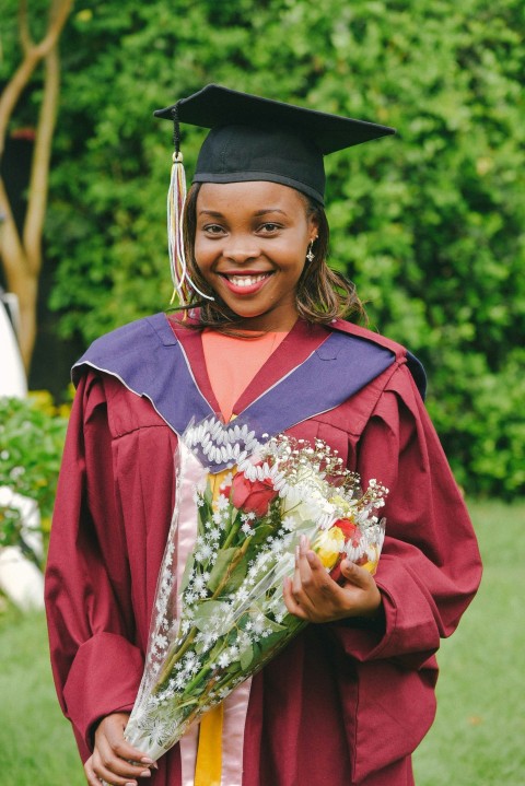 a woman in a graduation gown holding a bouquet of flowers