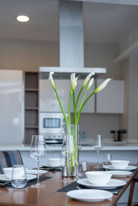 a dining room table with a vase of flowers on it MNcd