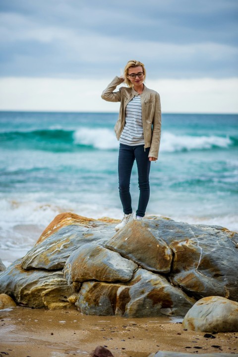 a woman standing on top of a rock near the ocean