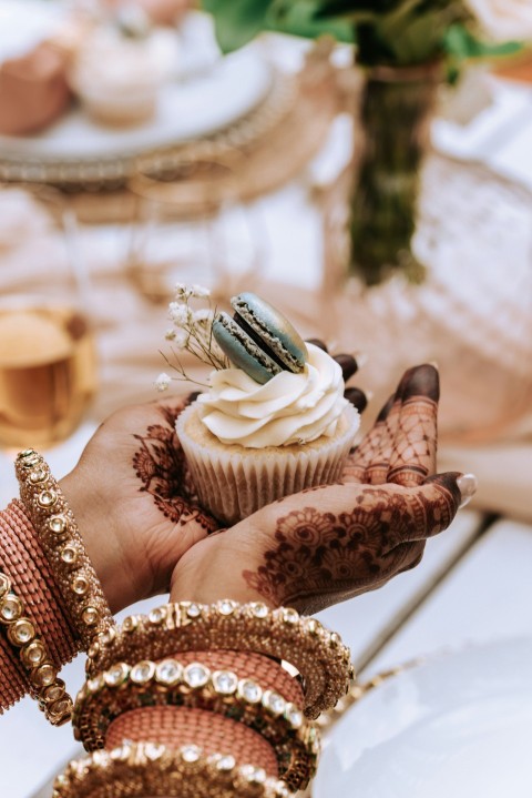 a person holding a cupcake in their hand zlIHOBgKH