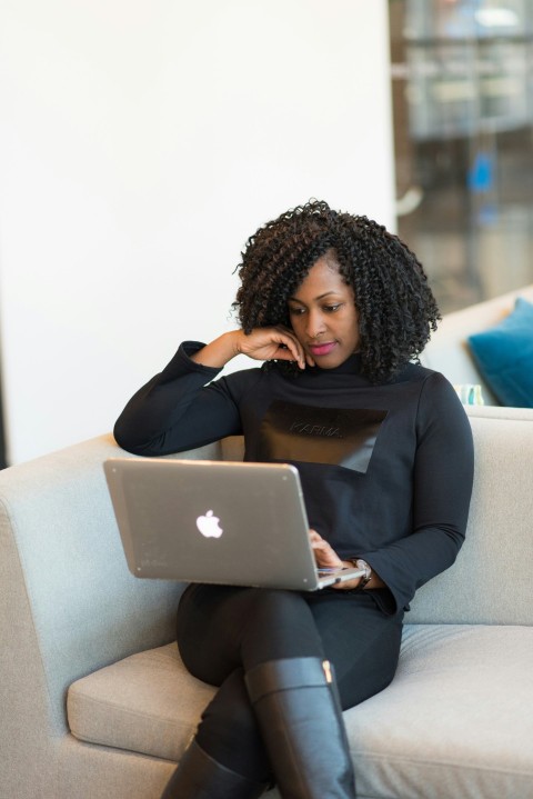 woman in black coat using macbook