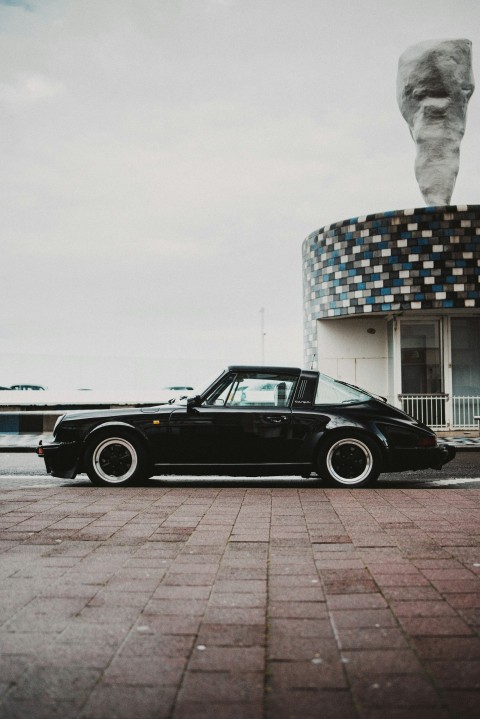 black coupe parked beside white concrete building during daytime 9xDHMDG