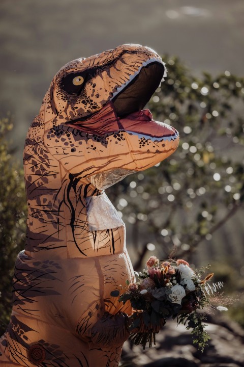 an inflatable dinosaur holding a bouquet of flowers