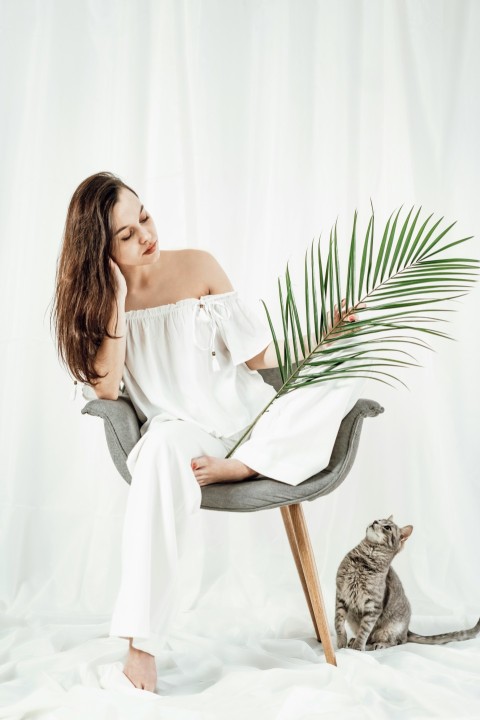 a woman sitting on a chair next to a cat