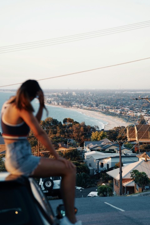 woman in black crop top sitting on car