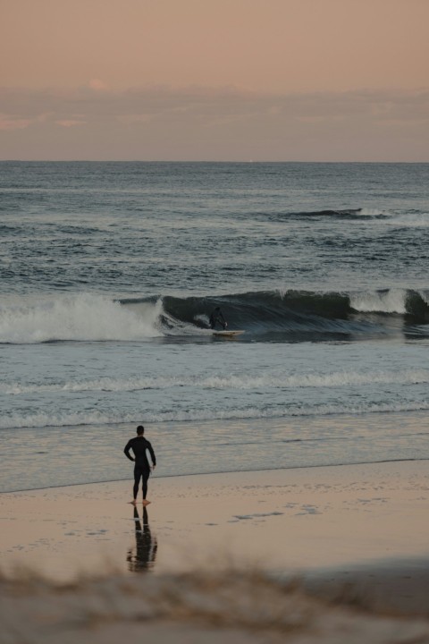 a person standing on a beach next to the ocean fa