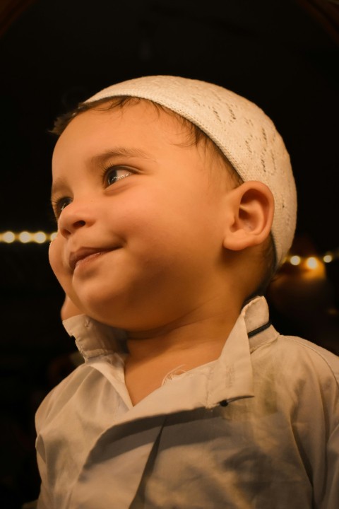 a little boy with a white headband smiling  G