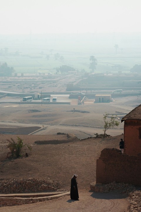 a person standing on a dirt road near a building