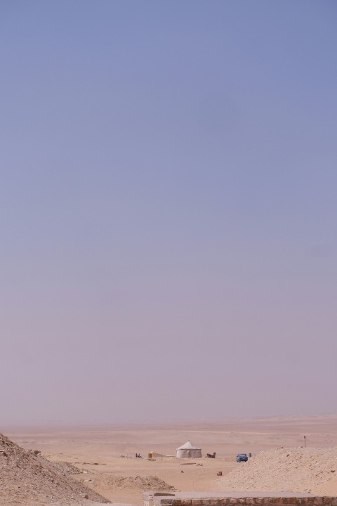 a desert scene with a few vehicles in the distance