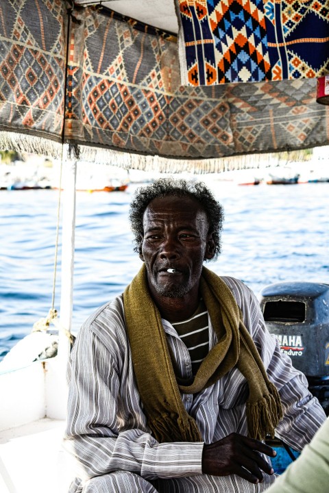 a man sitting on a boat smoking a cigarette