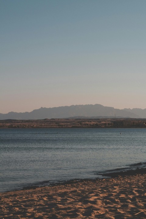 body of water near mountain during daytime