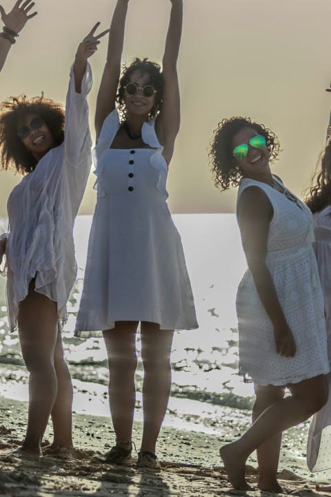 a group of women standing on top of a sandy beach