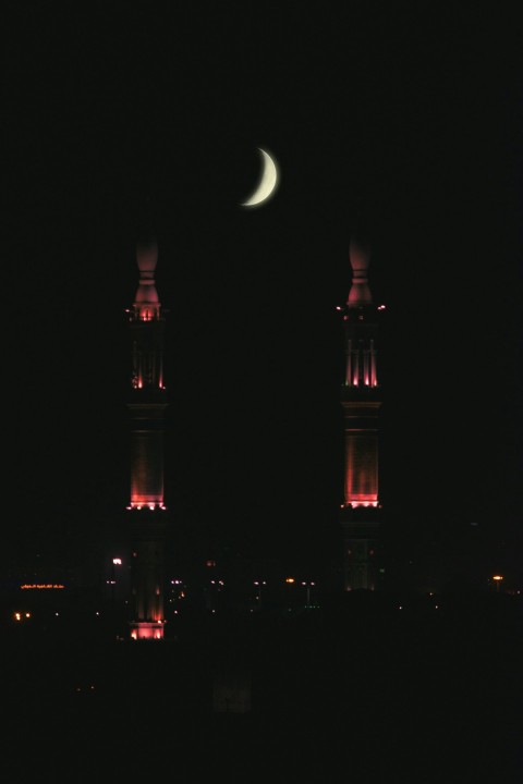 crescent moon above buildings lighted at night