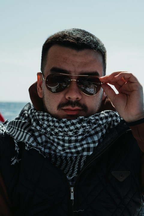 a man wearing sunglasses and a checkered scarf