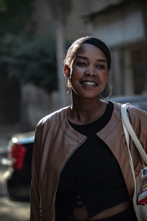 a woman in a black top and a brown leather jacket