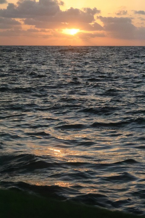 a body of water with waves and a sunset