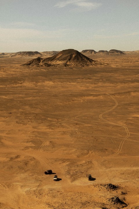 a dirt field with a hill in the distance