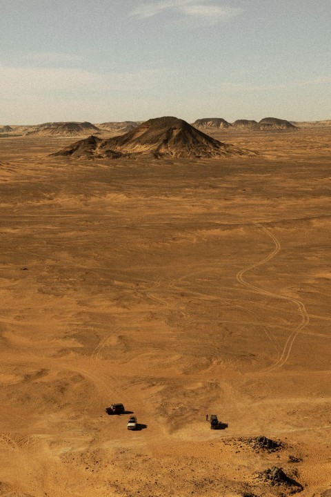 a dirt field with a hill in the distance