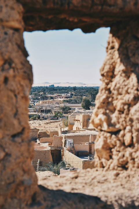 a view of a village through a hole in a rock wall