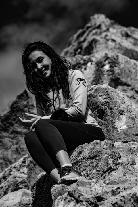 a woman sitting on top of a large rock