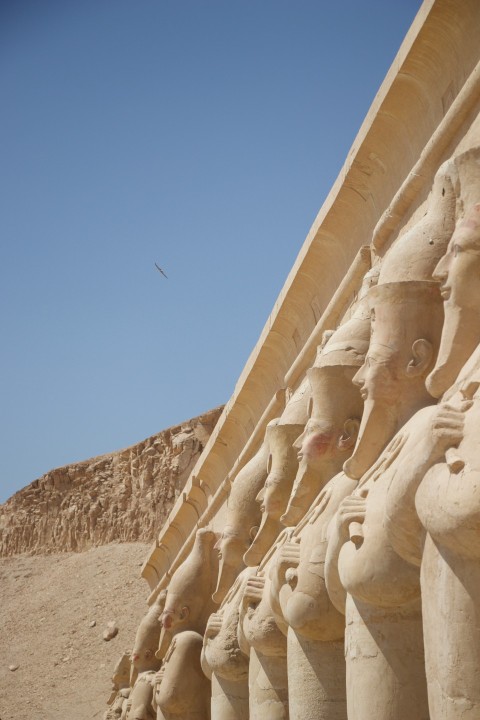 a row of statues in front of a pyramid PfJ2