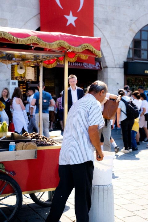 a man standing next to a food stand OEPeFxh