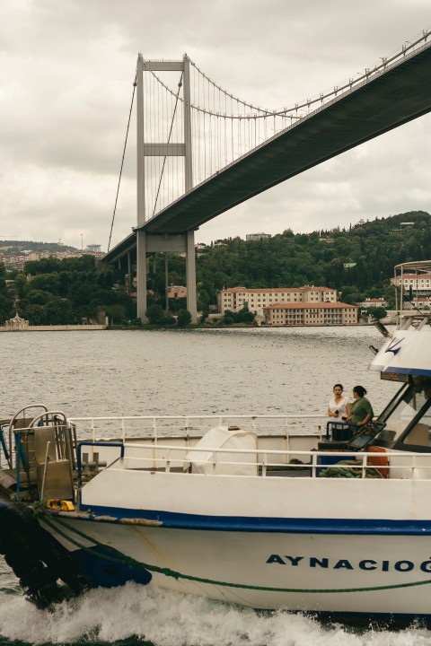 a white and blue boat traveling under a bridge