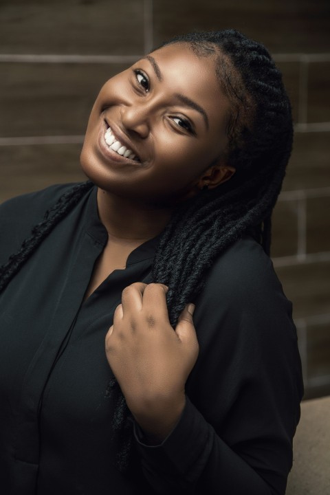 a smiling woman with braids on her hair