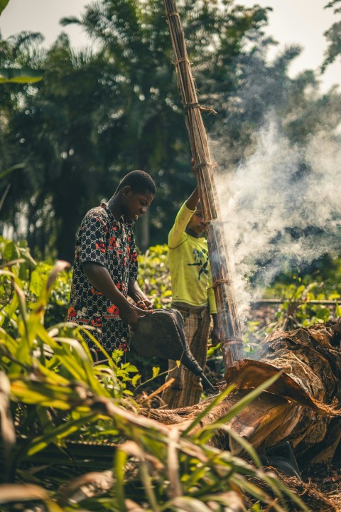 a man standing next to a boy near a fire