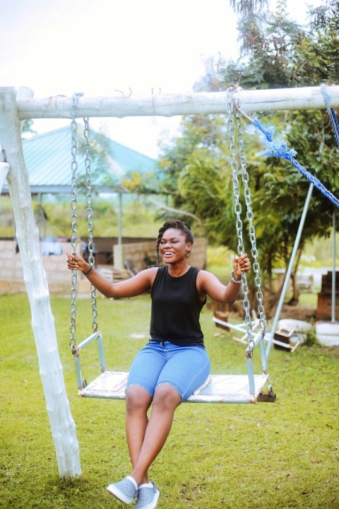 a woman sitting on a swing in a park 7a