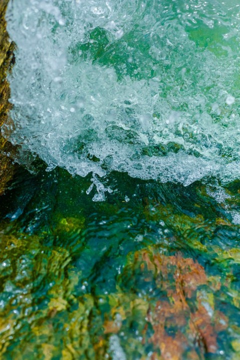 a close up of a wave coming over a rock