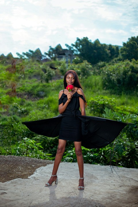 a woman holding a flower and posing for the camera