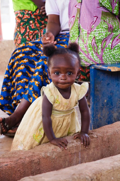 a little girl sitting on a brick wall nx7Vc2P