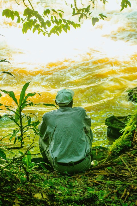 a man sitting on the bank of a river