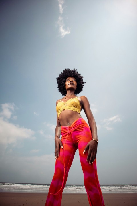 a woman standing on a beach in a yellow top