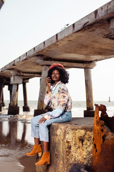 a woman sitting on a wall talking on a cell phone