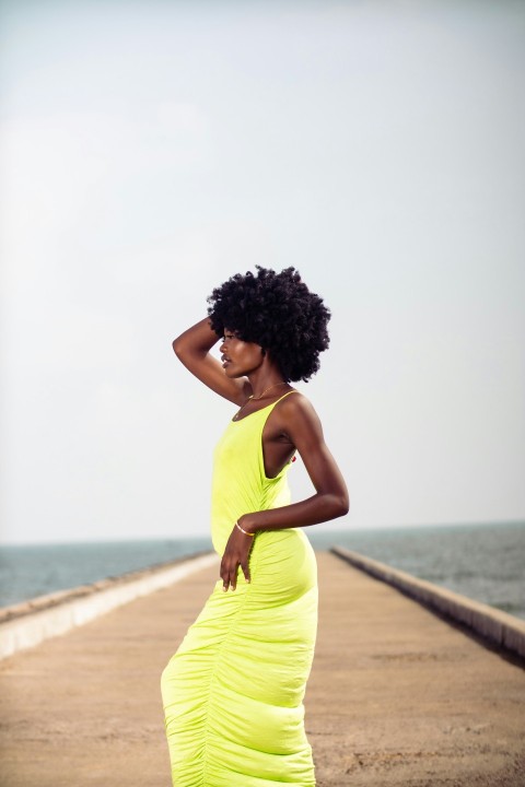 a woman in a yellow dress standing on a pier