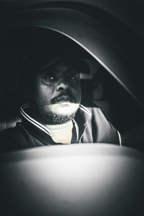 a man sitting in a car with a hat on