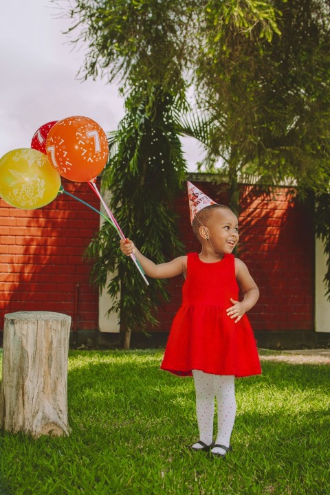 a little girl holding a bunch of balloons