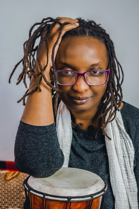 a woman with glasses is holding a drum ps