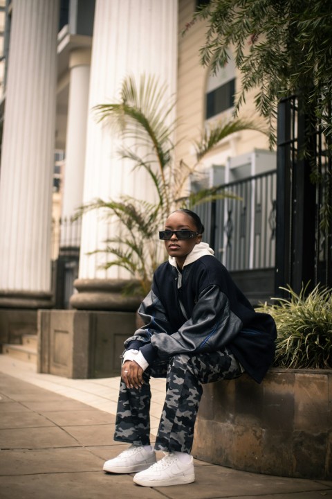 a man sitting on a wall wearing sunglasses