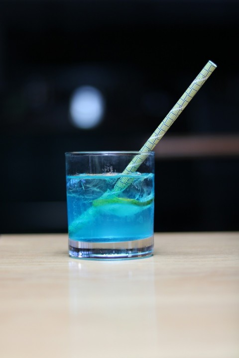 blue drinking glass with ice cubes and straw