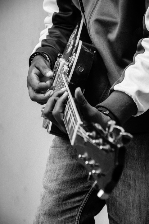 person playing guitar in grayscale photography