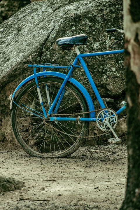 a blue bicycle parked next to a large rock