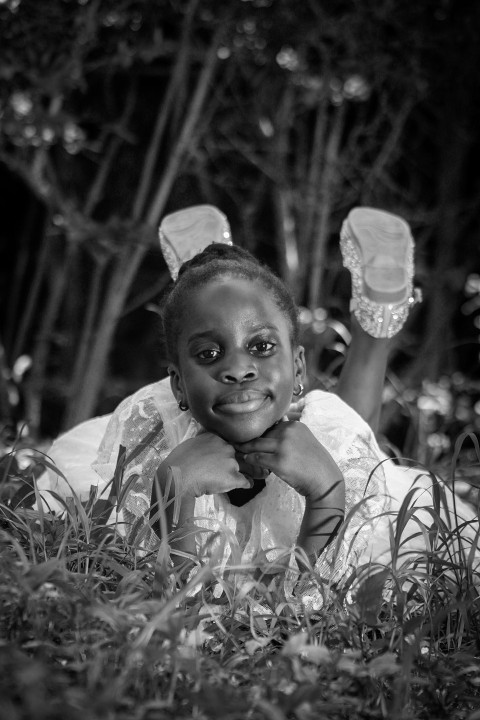 a little girl laying in the grass with her feet up