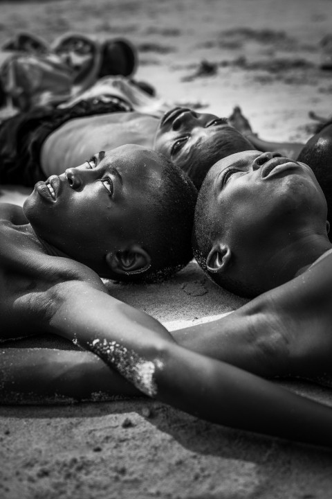 a group of people laying on top of a sandy beach